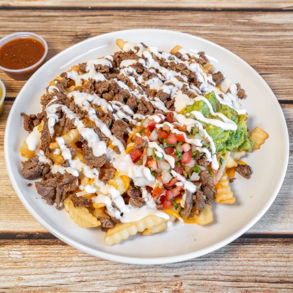 Carne asada fries topped with guacamole, pico de gallo, and sour cream, with two dipping sauces.