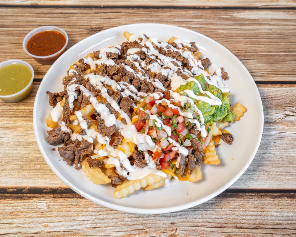 Carne asada fries topped with guacamole, pico de gallo, and sour cream, with two dipping sauces.