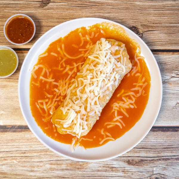 A cheese-covered burrito in red sauce on a white plate, with green and red salsas.