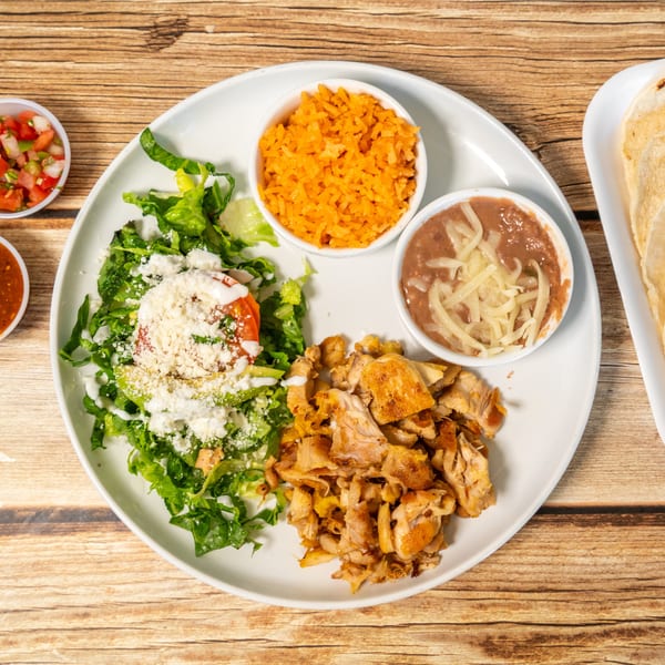A Mexican dish with grilled chicken, rice, beans, salad, salsa, pico de gallo, and tortillas.