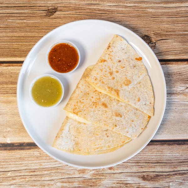 Cheese quesadillas with red and green salsa on a white plate, on a wooden table.
