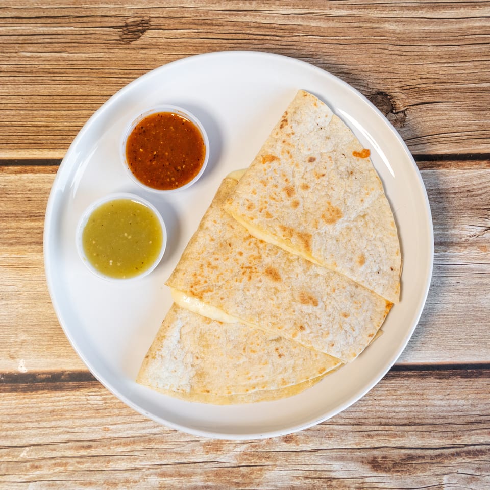 Cheese quesadillas with red and green salsa on a white plate, on a wooden table.